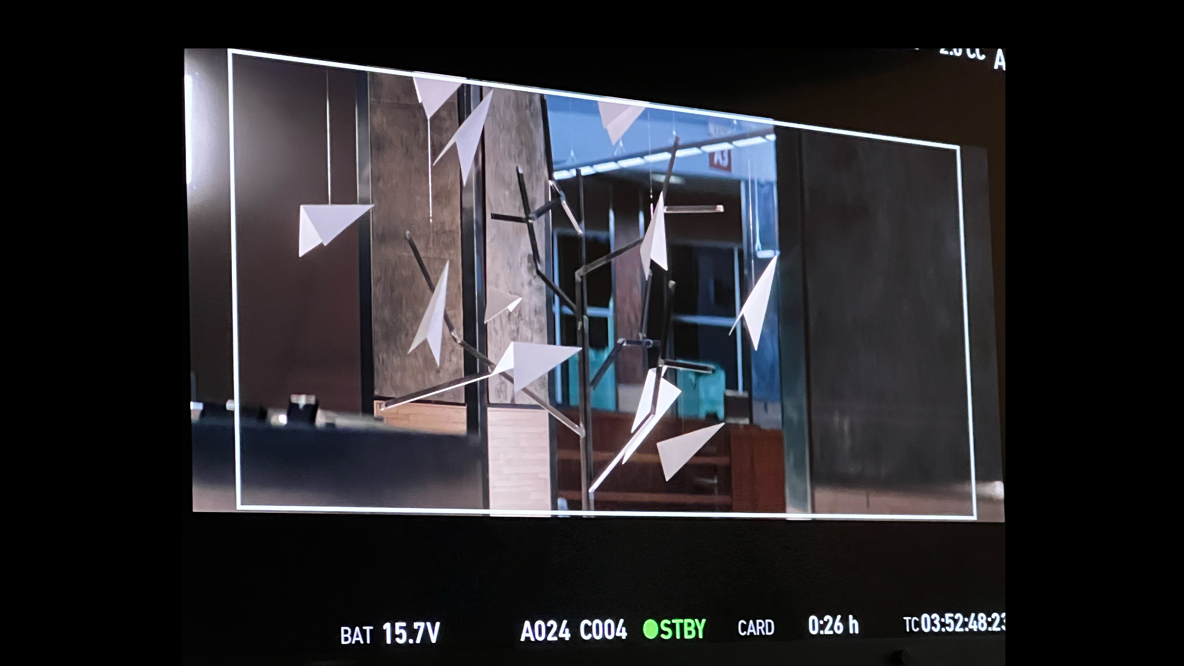Paper-plane sculpture viewed through a production monitor
